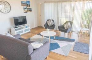 a living room with a couch and chairs and a tv at Glistening Waters in Tathra
