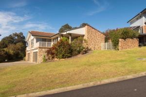 a large brick house with a grassy yard at Glistening Waters in Tathra