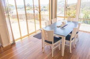 a dining room table with chairs and a large window at Glistening Waters in Tathra