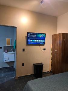 a bedroom with a flat screen tv on the wall at Loft 4 Mobiliado e Individual com Garagem 3min do centro in Dourados