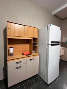 a kitchen with a white refrigerator and a wooden cabinet at Loft 4 Mobiliado e Individual com Garagem 3min do centro in Dourados