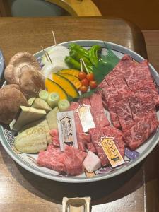 a plate of meat and vegetables on a table at 二食付き最高ランクの飛騨牛と地元野菜の炭火焼きディナーそしてプライベート檜風呂を体験できる個室古民家Resort Villaゲストハウスつぐや in Kurono