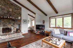 a living room with a couch and a stone fireplace at Rustic Mountain view Cabin 5 mins to Ski Area! in Windham