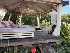 a bed under a pergola on a wooden deck at L Effet Mer Cocon climatisé avec terrasse et jardin privés Piscine in Audenge