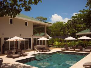 a pool with chairs and umbrellas next to a house at The Providence Hotel Boutique - Adults Only in San Andrés