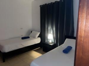 ein Schlafzimmer mit zwei Betten und einer Lampe und Vorhängen in der Unterkunft Don César in Las Terrenas + 13 Fotos