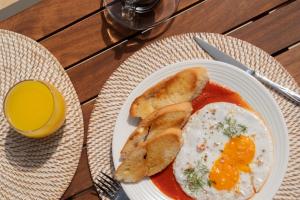a plate of eggs and bread and a glass of orange juice at The Providence Hotel Boutique - Adults Only in San Andrés