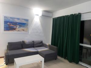 ein Wohnzimmer mit einer Couch und einem grünen Vorhang in der Unterkunft Don César in Las Terrenas