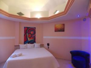 Un dormitorio con una cama blanca y una pintura en la pared en Hotel Express Alejandría, en Xalapa