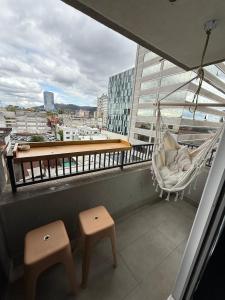 ein Balkon mit zwei Hockern und einer Hängematte an einem Gebäude in der Unterkunft Epic Hotel Temuco in Temuco