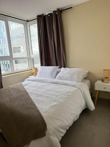 ein Schlafzimmer mit einem Bett mit weißer Bettwäsche und einem Fenster in der Unterkunft Epic Hotel Temuco in Temuco