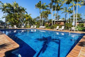 a large swimming pool with chairs and palm trees at Brisbane Gateway Resort in Rochedale
