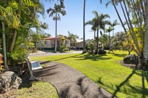 a park with a bench in a yard with palm trees at Brisbane Gateway Resort in Rochedale