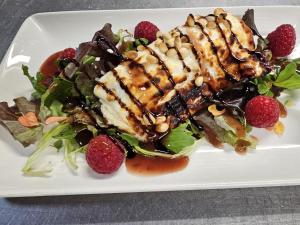 Ein weißer Teller mit einem Salat mit Fleisch und Beeren in der Unterkunft The Schoolhouse Hotel in Swindon