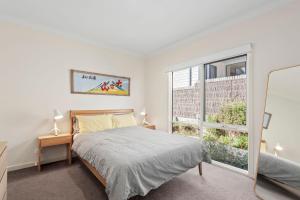 a bedroom with a bed and a large window at Kassandra in Point Lonsdale