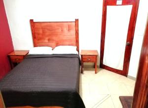 a bedroom with a bed and two tables and a mirror at La Gloria Hotel Xilitla in Xilitla
