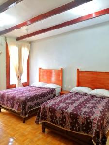 a bedroom with two beds and two windows at La Gloria Hotel Xilitla in Xilitla