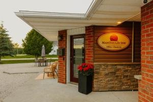 a restaurant with a sign on the side of a building at Manitoulin Inn in Mindemoya