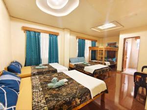 a room with three beds with blue curtains at Mountain Lodge within Town Proper! in Sagada