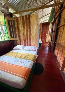 a bed in a room with wooden walls at Playa Verde Lodge in Bahía Solano