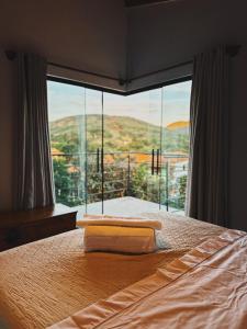 a bedroom with a bed with a large glass window at Vista dos Vales - Vila Real do Vau, próximo a São Gonçalo, Milho Verde, Diamantina in Diamantina