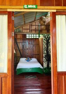 a room with a bed in a wooden house at Playa Verde Lodge in Bahía Solano