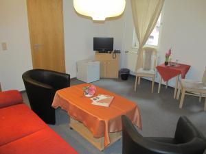 un soggiorno con tavolo, sedie e TV di Pension Mahrets Puppenstube a Eisenach