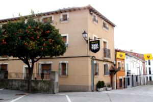 a building with an orange tree and a clock on it at Hosteria Gante in Jarandilla de la Vera