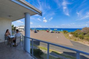 a man and woman sitting at a table on a balcony looking at the ocean at Nautilus 5 in Hawks Nest