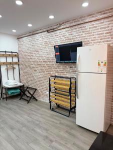 a white refrigerator in a room with a brick wall at Elegant Studio - Ideal for Couples in Mazagran