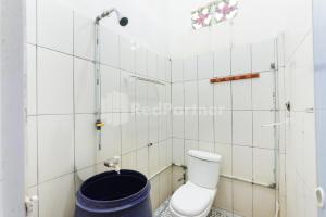 a bathroom with a toilet and a bucket at Ombai Guest House 27 Syariah Mitra RedDoorz in Kertapati +16 photos