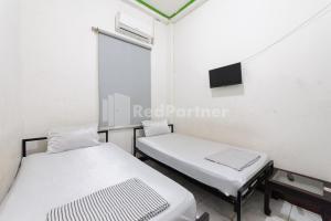 a hospital room with two beds and a tv at Ombai Guest House 27 Syariah Mitra RedDoorz in Kertapati