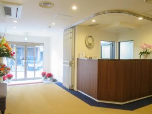 an office lobby with a reception desk and a clock on the wall at ホテルリブマックスBudget川崎大師 in Kawasaki