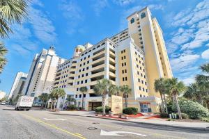 a large white building on a city street with palm trees at Camelot by the Sea Resort Unit 1505 with Oceanfront Balcony in Myrtle Beach