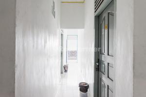 a hallway with white walls and a door at Hotel Idayu Natuna Palembang RedPartner in Palembang