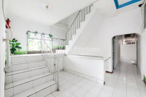 a staircase in a room with white tile floors at Hotel Idayu Natuna Palembang RedPartner in Palembang