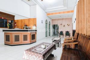 a living room with a table and a kitchen at Hotel Idayu Natuna Palembang RedPartner in Palembang