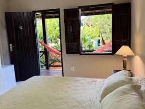 a bedroom with a bed with a lamp and two windows at Pousada Bemvirá in Arraial d'Ajuda +149 photos