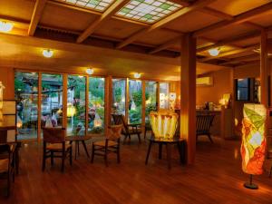 a dining room with tables and chairs and windows at Kamei no Yu in Yamanouchi