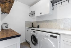 a white laundry room with a washer and dryer at Amore Manor Auckland in Auckland