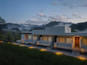 a house on a hill with mountains in the background at NINE PEAKS in Jiuzhaigou