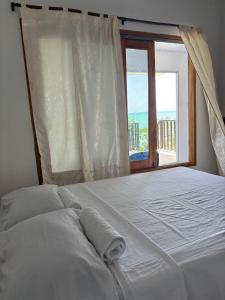 a white bed with a window with a view of the ocean at La Casa de la Tortuga in San Onofre +8 photos