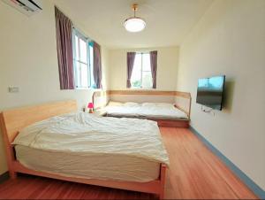 a bedroom with two beds and a flat screen tv at Hakka Eco-farm 雅歌園民宿食農教育有機農場 in Wanluan +91 photos
