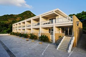 a building with a parking lot in front of it at Hillside Sea View Resort Villa Gushikumui in Motobu