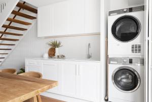 a kitchen with white cabinets and a washer and dryer at Crystal Pacific Palm Beach in Gold Coast