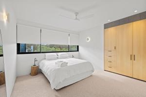 a white bedroom with a bed and a large window at Betula in Tilba Tilba