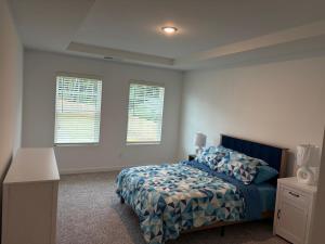 a bedroom with a bed with a blue comforter and two windows at Modern Comfort in Morrow