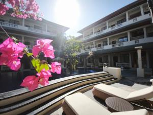 a building with benches and pink flowers in front of it at Casa Mysa Hotel Kuta in Kuta