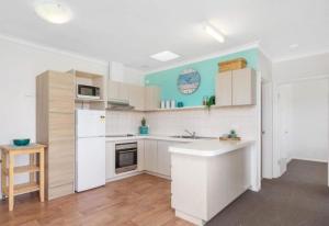 a kitchen with white cabinets and a white refrigerator at Ocean Views in Rockingham +5 photos