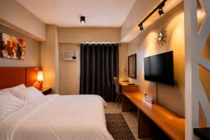 a hotel room with a bed and a flat screen tv at MIGAs Haven at Sunvida Tower across SM City in Cebu City